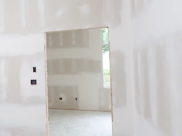 Close view of finished drywall seams around a doorway, ready for primer and paint