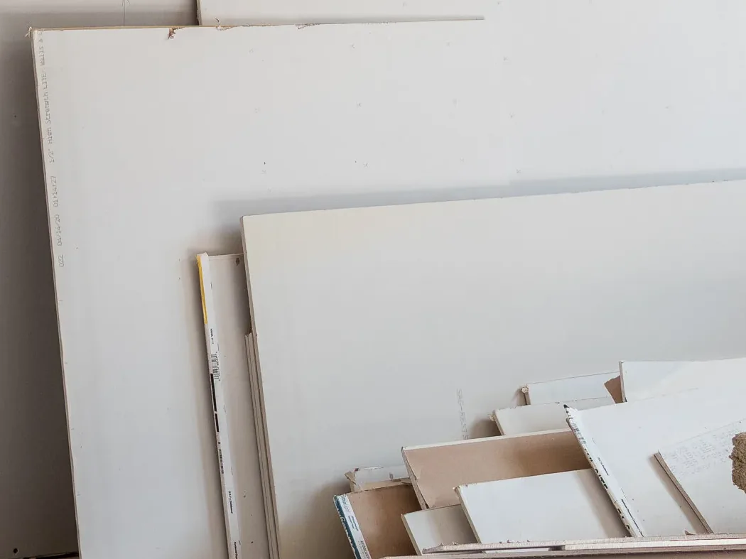 Sheets of drywall stacked against an installed drywall wall