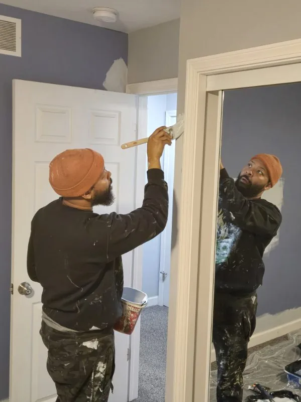 A painter brushing paint onto a door frame inside a home